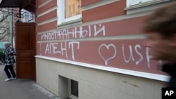 FILE - A man passes by the office of "Memorial" rights group in Moscow, Russia, Nov. 21, 2012. The building has the words “Foreign Agent (Loves) USA” spray-painted on its facade.