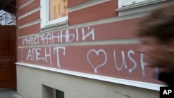 FILE - A man passes by the office of "Memorial" rights group in Moscow, Russia. The building has the words “Foreign Agent (Loves) USA” spray-painted on its facade.