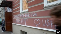 FILE - A man passes by the office of "Memorial" rights group in Moscow, Russia. The building has the words "Foreign Agent (Loves) USA" spray-painted on its facade.