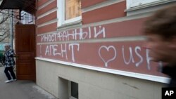 FILE - A man walks by the office of "Memorial" rights group in Moscow, Russia, Nov. 21, 2012. The building's facade is seen defaced with graffiti reading “Foreign Agent (Loves) USA.”