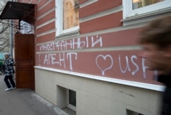 FILE - A man passes by the office of "Memorial" rights group in Moscow, Russia. The building has the words "Foreign Agent (Loves) USA" spray-painted on its facade.