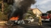 Vatrogasci gase automobil koji je pogođen u gradu Aškelonu na jugu Izraela (Foto: Menahem KAHANA/AFP)