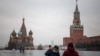 FILE - A man puts on a protective face mask as he stands with another person in a deserted Red Square in Moscow, Russia, Oct. 28, 2021.