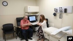 FILE - Dr. Jori Fleisher, neurologist, examines Thomas Doyle, 66, at the Rush University Medical Center in Chicago, July 9, 2019. 