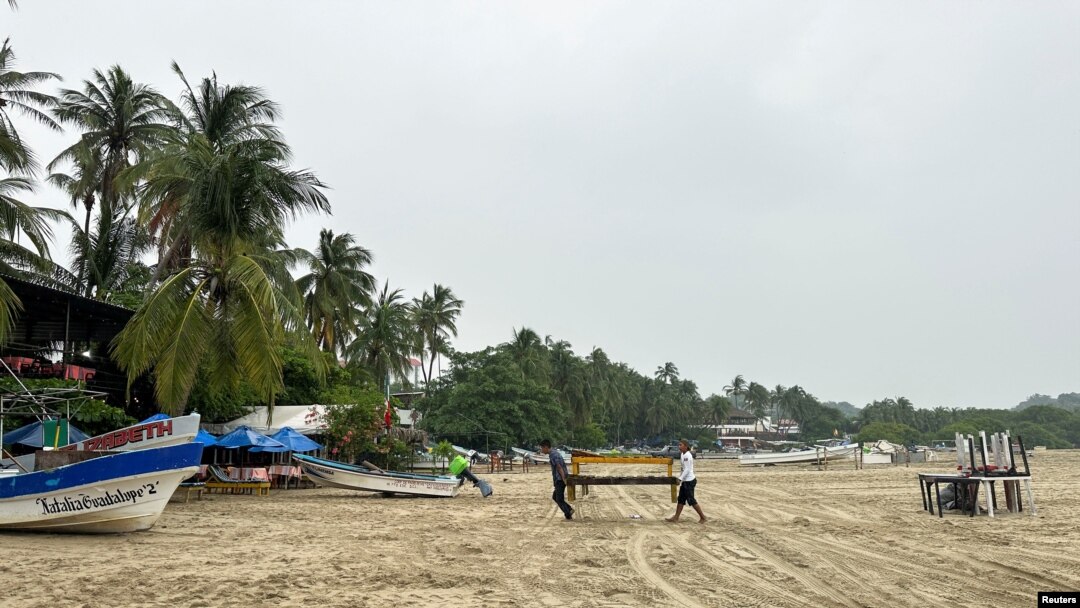 Residents carry wooden tables ahead of the arrival of Storm John, in Puerto Escondido, Oaxaca state, Mexico, Sept. 23, 2024.