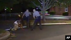 In this Aug. 24, 2013, photo made from a police dash camera video and released by the Dover Police Department, Dover Police Cpl. Thomas Webster, center, kicks Lateef Dickerson in the face as Dickerson is following orders to get on the ground during an arr