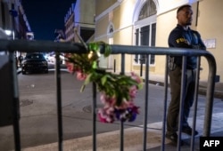 A member of the FBI stands near a bouquet of flowers tied to a fence a block from Bourbon Street in New Orleans, Louisiana, after at least 15 people were killed during an attack early in the morning of Jan. 1, 2025.