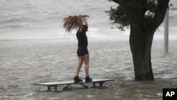 當艾薩克颶風8月28日快要在新奧爾良地區登陸的時候，一名婦女站在龐恰特雷恩湖湖畔沿湖公路上幾乎被巨浪淹沒的長椅上。
