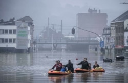 Des personnes utilisent des radeaux en caoutchouc dans les eaux de crue après que la Meuse soit sortie de son lit lors de fortes inondations à Liège, en Belgique, jeudi 15 juillet 2021.