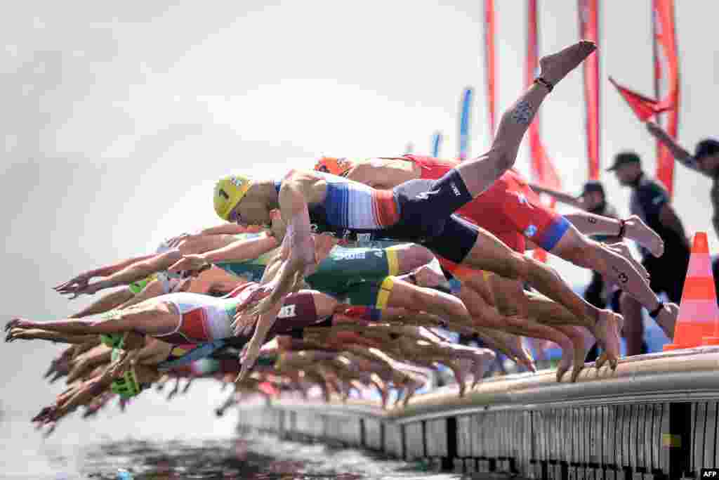 France&#39;s Vincent Luis (No1 in Yellow) jumps into Geneva Lake with competitors at the start of the ITU World Triathlon Grand Final in Lausanne, Switzerland, Aug. 31, 2019.