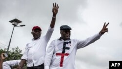 Félix Tshisekedi (à droite), leader de l'Union pour la démocratie et le progrès social (UDPS) et son allié de l'Union pour la nation congolaise (UNC), Vital Kamerhe (à gauche), saluent leurs partisans après leur retour à Kinshasa, le 27 novembre 2018.
