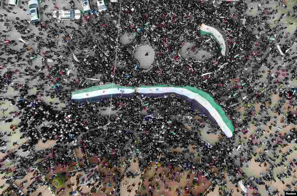 People carry opposition flags during a demonstration, marking the 10th anniversary of the start of the Syrian conflict, in the opposition-held Idlib.