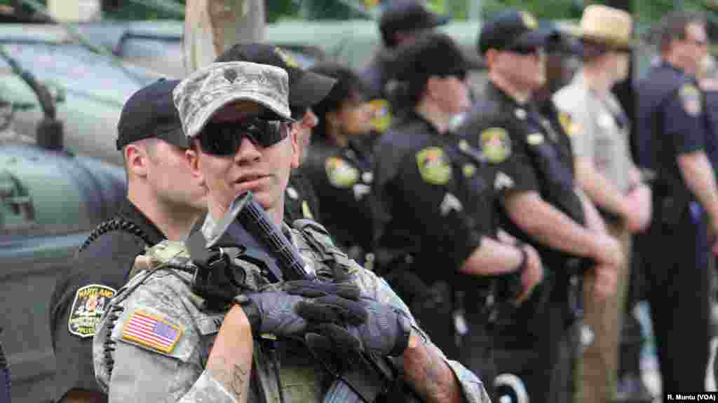 Police officers and National Guard troops stand watch as protesters gathers in Baltimore, May 2, 2015.