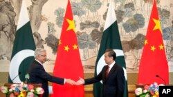 FILE - Pakistan's Foreign Minister Khawaja Muhammad Asif, left, and Chinese Foreign Minister Wang Yi reach to shake hands at the end of a joint press conference at the Diaoyutai State Guesthouse in Beijing, Friday, Sept. 8, 2017.