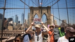 Para aktivis mengacungkan poster-poster di sepanjang Jembatan Brooklyn dalam pawai unjuk rasa memprotes kebijakan imigrasi pemerintahan Trump, di New York, 20 Juni 2018.