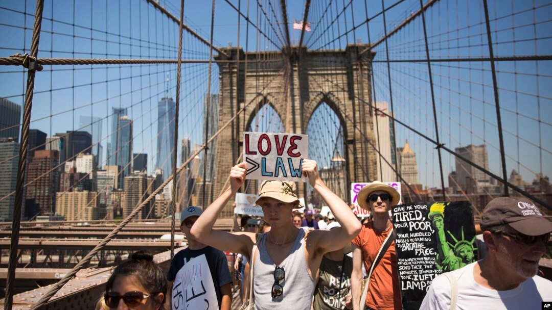 Para aktivis mengacungkan poster-poster di sepanjang Jembatan Brooklyn dalam pawai unjuk rasa memprotes kebijakan imigrasi pemerintahan Trump, di New York, 20 Juni 2018.