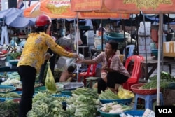 FILE - A woman hands money to a vegetables seller in a wet market in Phnom Penh, on August 29, 2020. (Tum Malis/VOA Khmer)