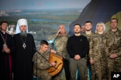 In this photo provided by the Ukrainian Presidential Press Office, President Volodymyr Zelenskyy, fifth from right, attends the Ukraine's Armed Forces Day prayer breakfast in Kyiv on Dec. 6, 2024.