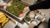 Para petugas sedang menyiapkan makanan di dapur untuk didistribusikan ke sekolah pada hari pertama pelaksanaan program makanan gratis di Jakarta, 6 Januari 2025. (Foto: Yasuyoshi CHIBA/AFP)