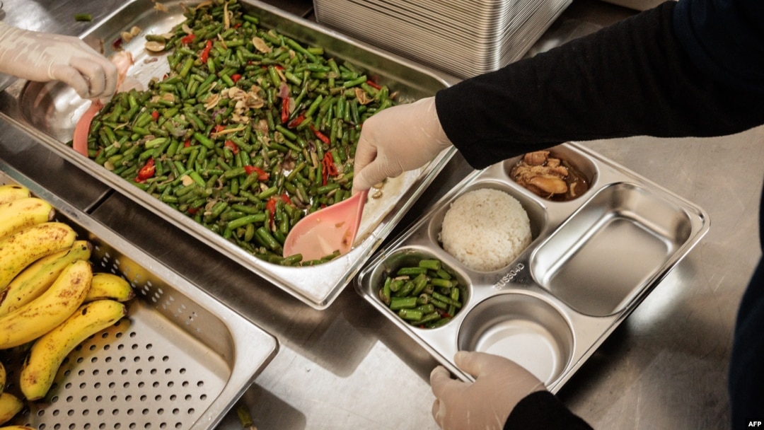 Para petugas sedang menyiapkan makanan di dapur untuk didistribusikan ke sekolah pada hari pertama pelaksanaan program makanan gratis di Jakarta, 6 Januari 2025. (Foto: Yasuyoshi CHIBA/AFP)