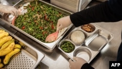 Para petugas sedang menyiapkan makanan di dapur untuk didistribusikan ke sekolah pada hari pertama pelaksanaan program makanan gratis di Jakarta, 6 Januari 2025. (Foto: Yasuyoshi CHIBA/AFP)