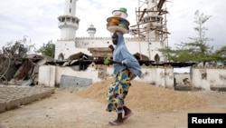 FILE - A girl walks past a destroyed mosque in the town of Mararaba, after the Nigerian military recaptured it from Boko Haram, in Adamawa state, May 10, 2015.