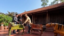 Nguyen Tan Phat shows his Tiger carving works to the customers ahead of the New Lunar New year in Hanoi, Vietnam January 18, 2022. (REUTERS/Stringer)