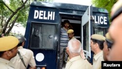 FILE - A man is escorted out of a police van outside a court in New Delhi.