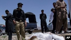 Pakistani security officials stand next to the covered body of Red Cross worker Khalil Dale in Quetta April 29, 2012.