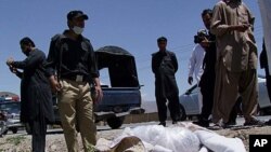 Pakistani security officials stand next to the covered body of British Red Cross physician Khalil Rasjed Dale in Quetta April 29, 2012.