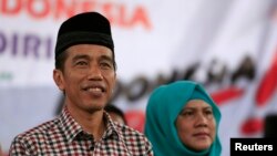 FILE - Indonesian presidential candidate Joko "Jokowi" Widodo (L) looks on as he sits with his wife Iriana during a campaign rally in Majalengka, West Java province.