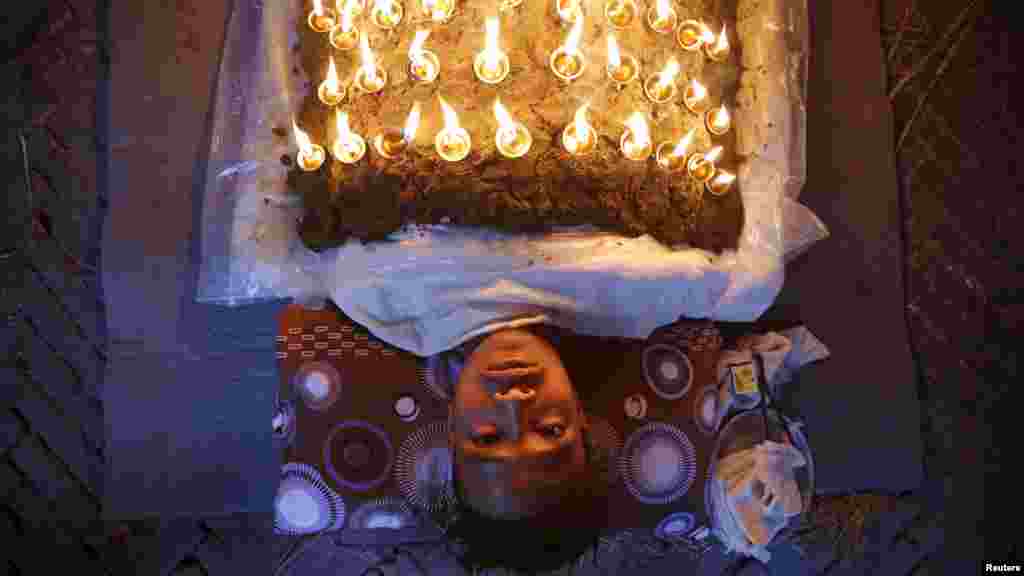 Seorang pemeluk Hindu meletakkan lampu minyak di atas tubuhnya, sebagai bagian dari ritual pada festival Hindu &quot;Dashain&quot;, di kota Bhaktapur, Nepal.