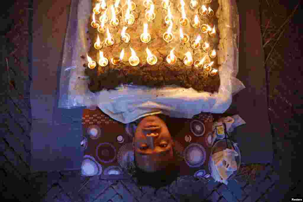 A devotee offers oil lamps on top of his body as part of a ritual during Dashain, the biggest religious festival for Hindus in Bhaktapur, Nepal.