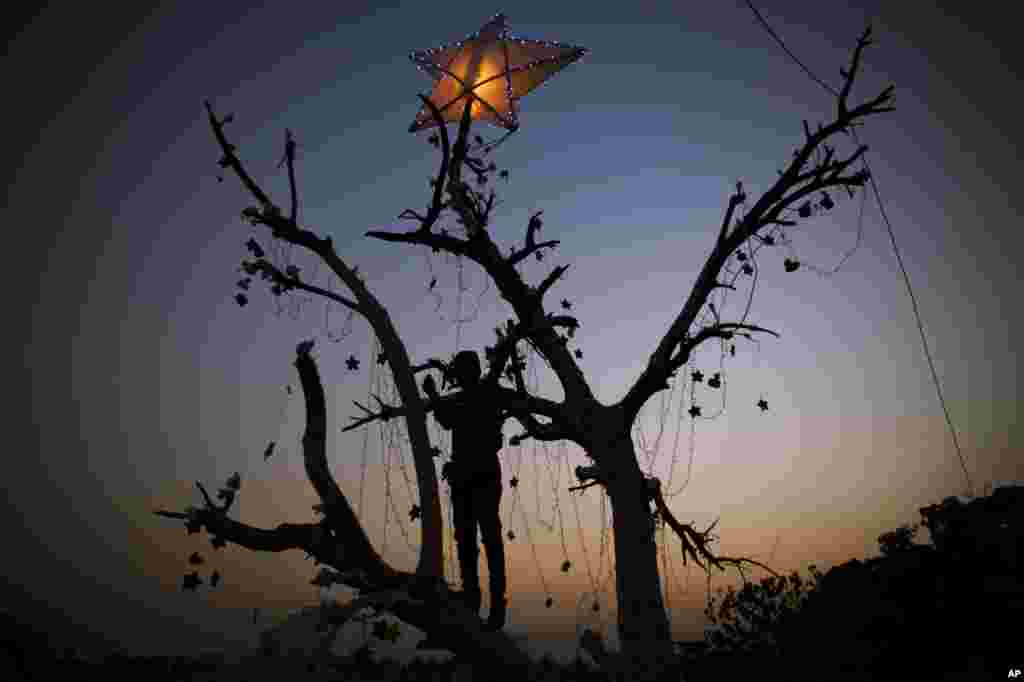 A Pakistani Christian boy decorates a tree in preparation for the upcoming Christmas holiday in Islamabad&#39;s slums.