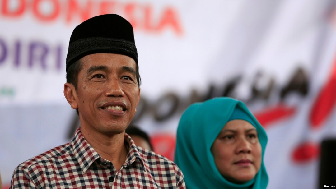 FILE - Indonesian presidential candidate Joko "Jokowi" Widodo (L) looks on as he sits with his wife Iriana during a campaign rally in Majalengka, West Java province.