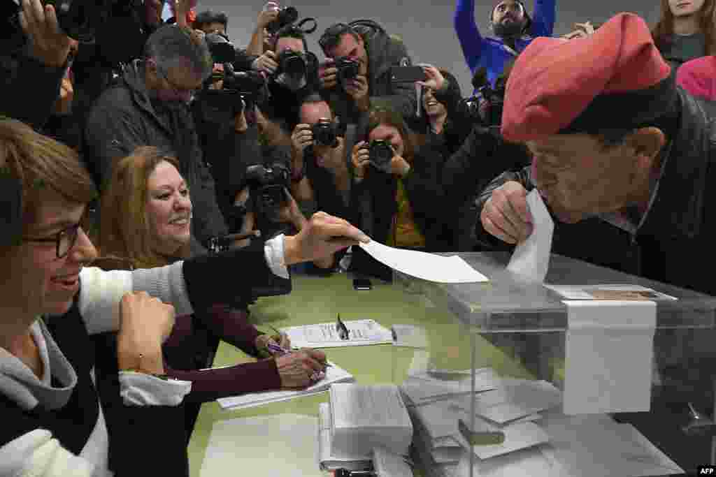 A man wearing an Catalan barretina hat kisses his ballot before casting his vote for the Catalan regional election at a polling station in Barcelona.