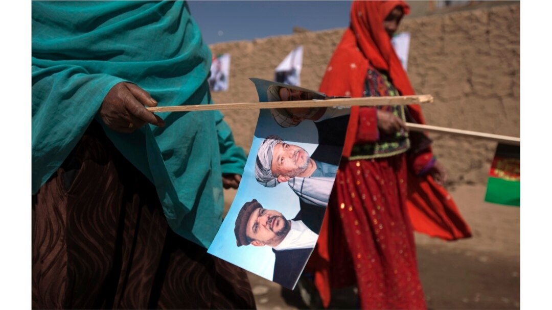 Perempuan etnis Hazara membawa gambar Presiden Afghanistan Hamid Karzai saat berjalan ke rapat umum kampanye di Bamiyan, Afghanistan tengah 16 Agustus 2009. (Foto: REUTERS/Adrees Latif)