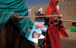 Perempuan etnis Hazara membawa gambar Presiden Afghanistan Hamid Karzai saat berjalan ke rapat umum kampanye di Bamiyan, Afghanistan tengah 16 Agustus 2009. (Foto: REUTERS/Adrees Latif)