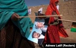 Perempuan etnis Hazara membawa gambar Presiden Afghanistan Hamid Karzai saat berjalan ke rapat umum kampanye di Bamiyan, Afghanistan tengah 16 Agustus 2009. (Foto: REUTERS/Adrees Latif)