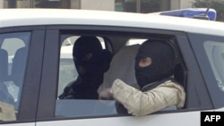 Неизвестные в полицейском автомобиле - предположительно Абделькадер Мера и его спутник. Люди в масках по бокам от задержаных - полицейские. Тулуза, 24 марта 2012