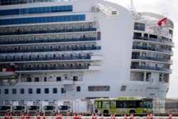 A bus carrying passengers leave the port after passengers disembarked from the quarantined Diamond Princess cruise ship Wednesday, Feb. 19, 2020, in Yokohama, near Tokyo. Passengers tested negative for COVID-19 started disembarking Wednesday. (AP Photo/Ja