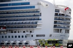 A bus carrying passengers leave the port after passengers disembarked from the quarantined Diamond Princess cruise ship Wednesday, Feb. 19, 2020, in Yokohama, near Tokyo. Passengers tested negative for COVID-19 started disembarking Wednesday. (AP Photo/Ja