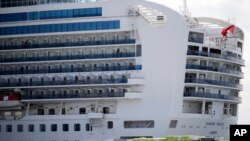 A bus carrying passengers leave the port after passengers disembarked from the quarantined Diamond Princess cruise ship Wednesday, Feb. 19, 2020, in Yokohama, near Tokyo. Passengers tested negative for COVID-19 started disembarking Wednesday. (AP Photo/Ja