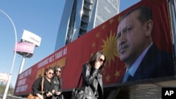 People walk past a huge billboard with an image of Turkey's President Recep Tayyip Erdogan that reads "Yes" in Turkish, in Ankara, Turkey, March 22, 2017. A referendum set for April 16 could boost Erdogan's powers.