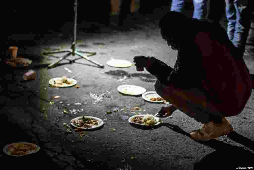 Para migran dan pengungsi makan malam dekat jalan bawah tanah di&nbsp; Ventimiglia, Italia. Banyak yang menunggu hingga malam untuk mencoba menyeberang ke Perancis.