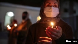 A believer wearing a protective mask holds a candle outside a church during an Orthodox Easter service, amid the coronavirus disease outbreak, in Marneuli, Georgia, April 18, 2020. 
