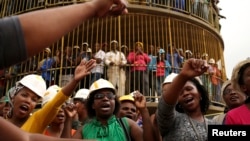Miners sing church hymns as they mourn their colleagues outside a shaft at Harmony Gold's Doornkop mine near Johannesburg, Feb. 6, 2014.