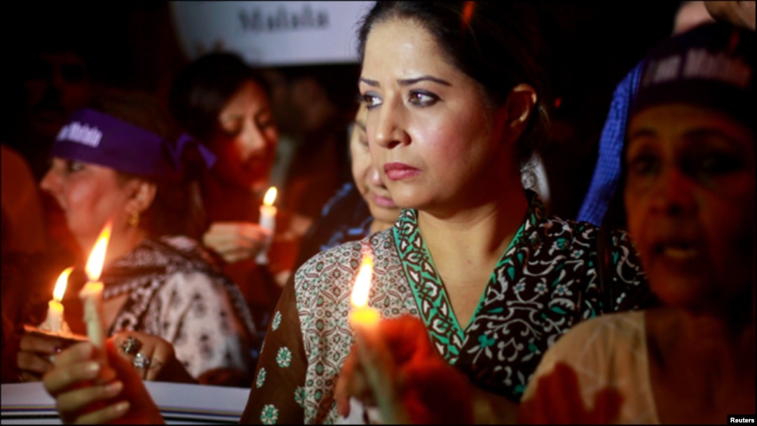 Women hold lighted candles during a rally