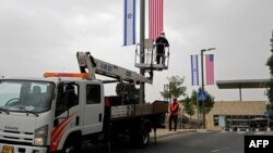 A worker installs Israeli and U.S. flags in front of the U.S. Consulate in Jerusalem which on Monday will formally be inaugurated as an embassy, in Jerusalem, May 7, 2018.