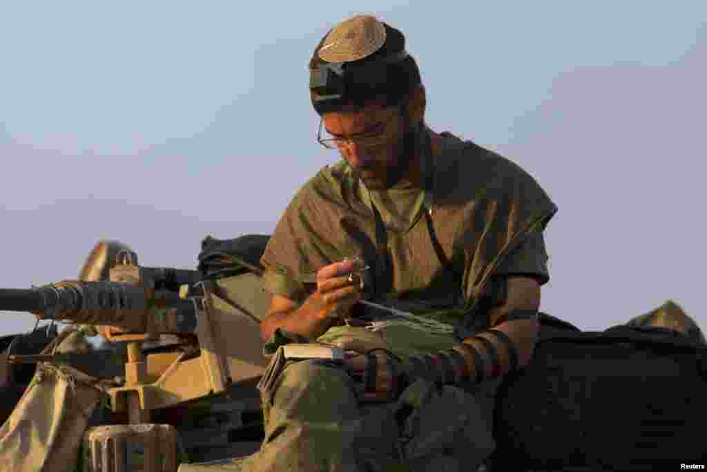 An Israeli soldier prays as he sits atop a tank near the border with Gaza, July 29, 2014.